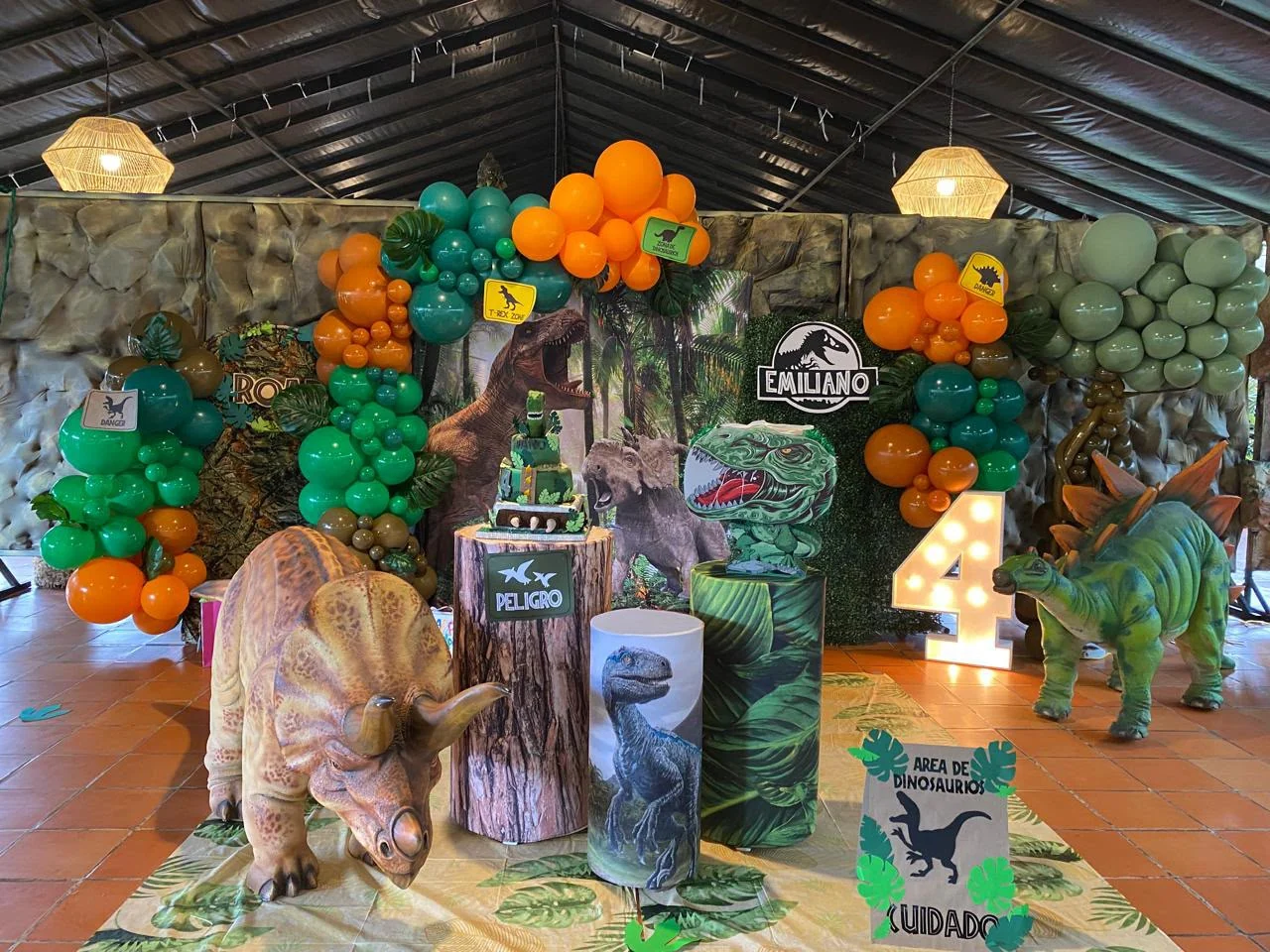 Decoración de cumpleaños con dinosaurios y globos verdes y naranjas
